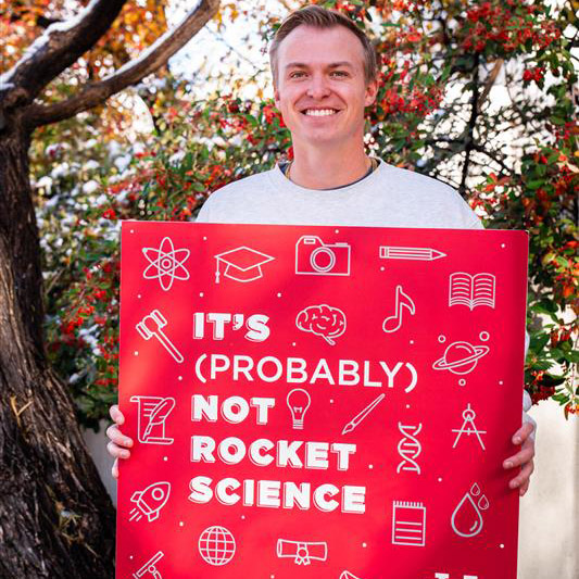 host Alexa Skonieski holding a large printed square of the podcast logo