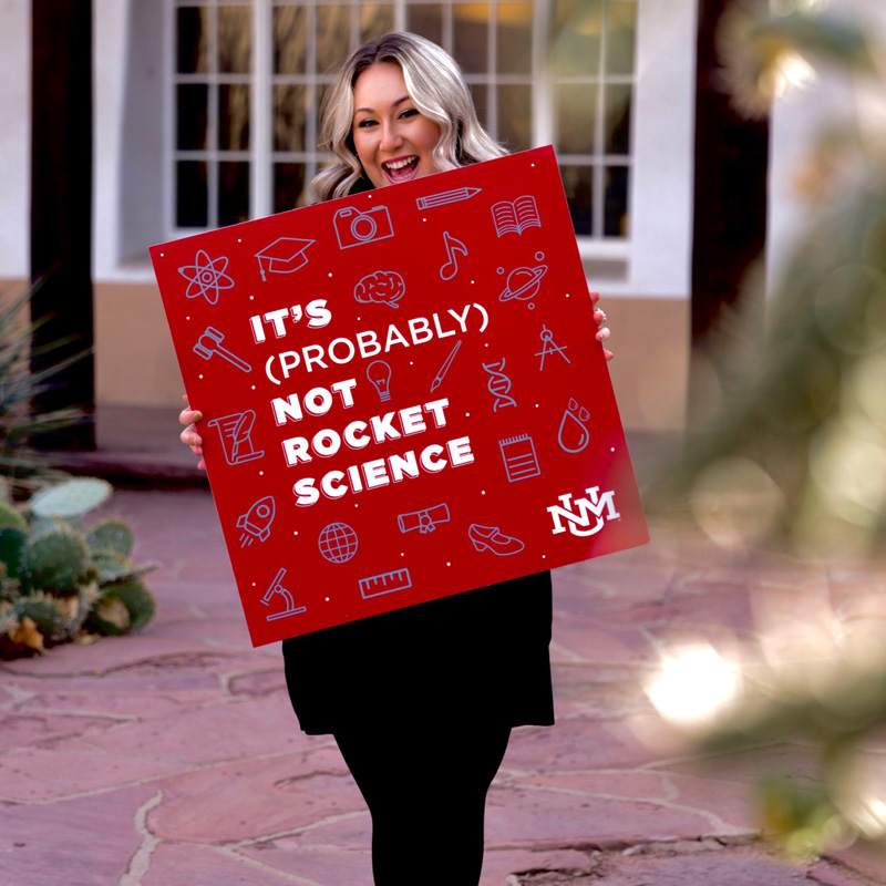 host Alexa Skonieski holding a large printed square of the podcast logo